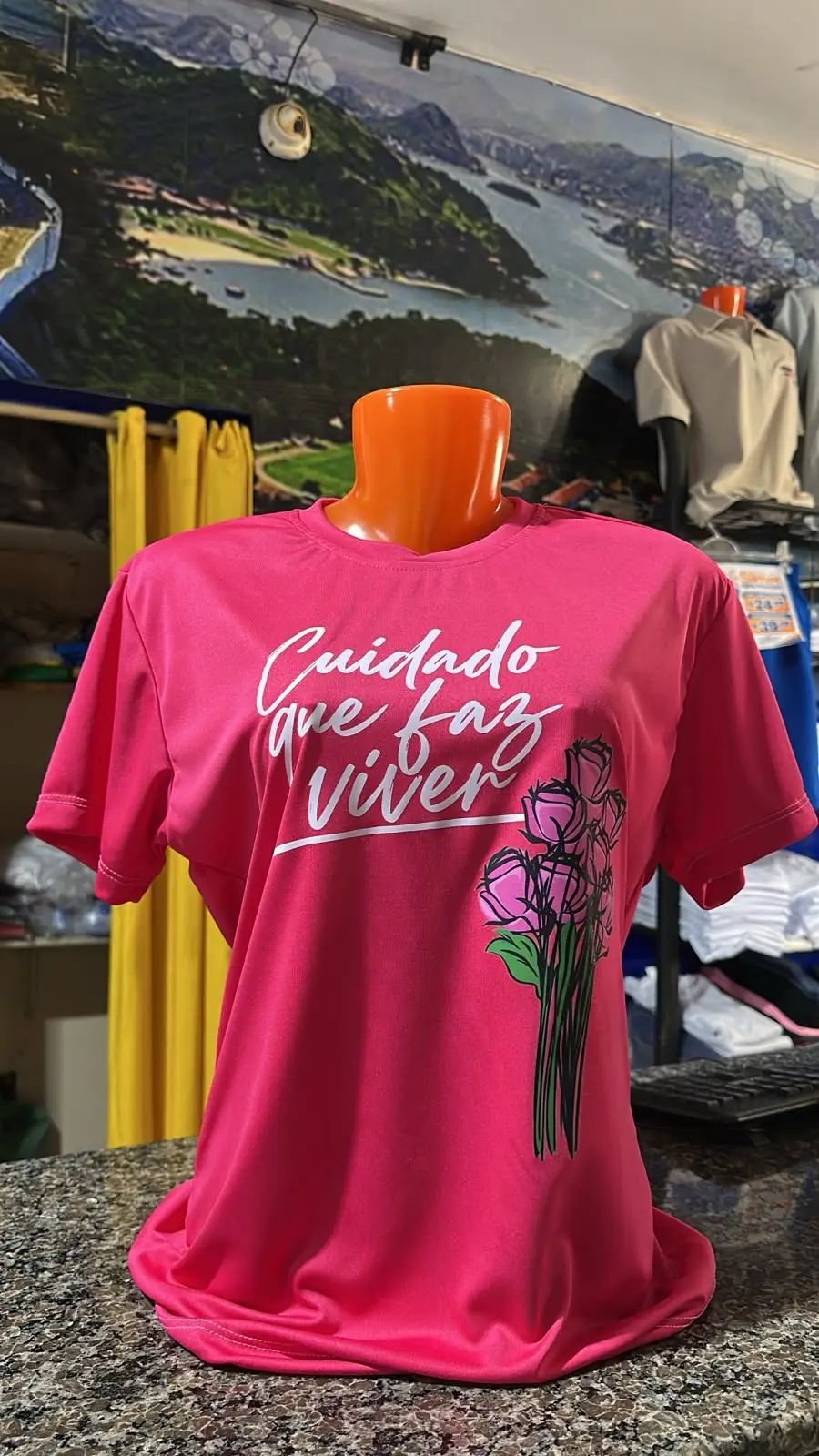 Camiseta rosa com a frase Cuidado que faz viver, fotografada em manequim na loja